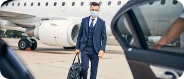 A suited traveler walking from a private jet toward a waiting luxury car.